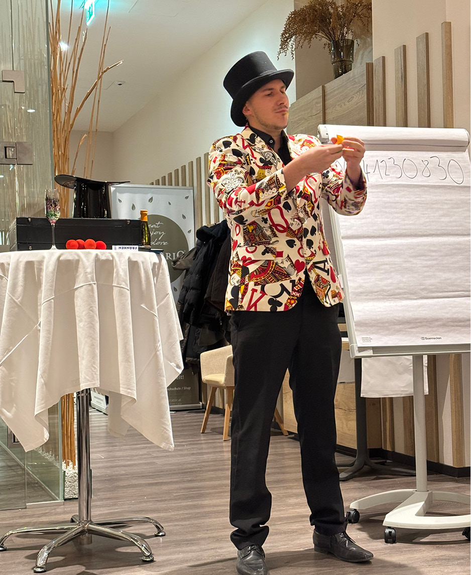 Illusian bei Magic Dinner Das Bild zeigt den Magier Illusian, wie er bei kulinario ein Zauberkunststück vorführt.