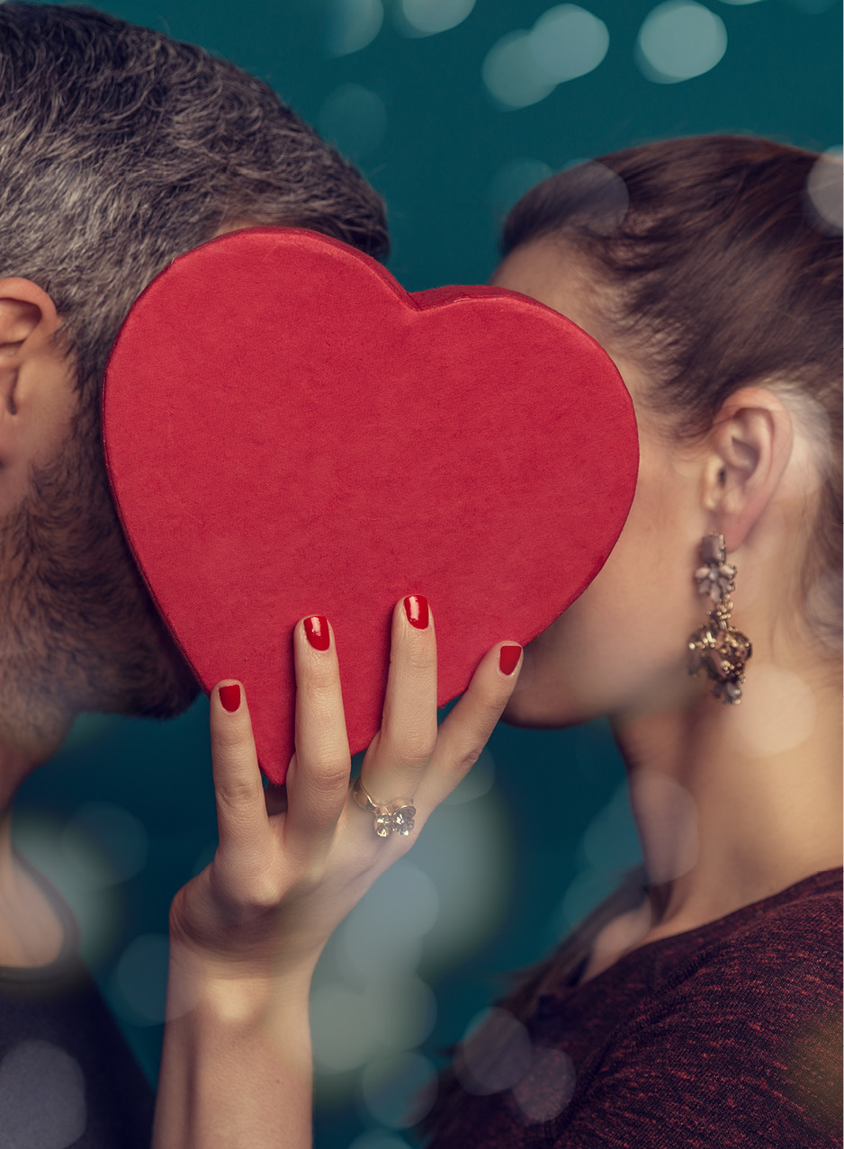 Das Bild zeigt einen Frauen- und einen Männerkopf hinter einem roten Herzen.