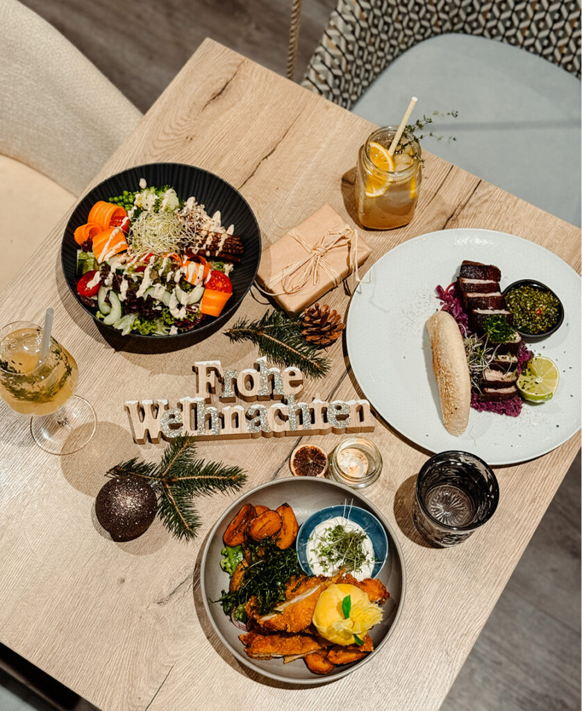 Das Bild zeigt einen weihnachtlich gedeckten Tisch mit dem Schriftzug 